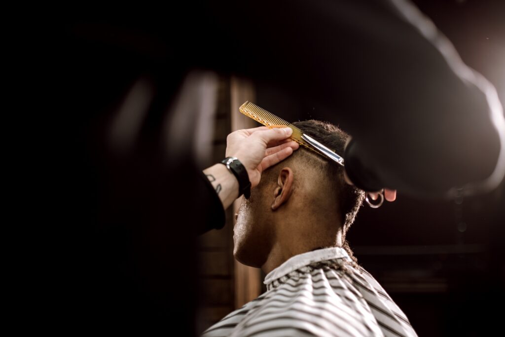 Parturi tasoittaa miehen hiuksia saksilla ja kamalla